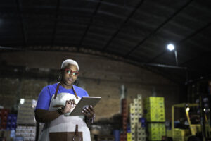 Feature image of a Black woman standing in a warehouse looking at her tablet